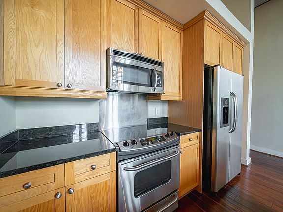 Custom cabinets with built-in microwave and dishwasher. Electric range with oven and full-size refrigerator.