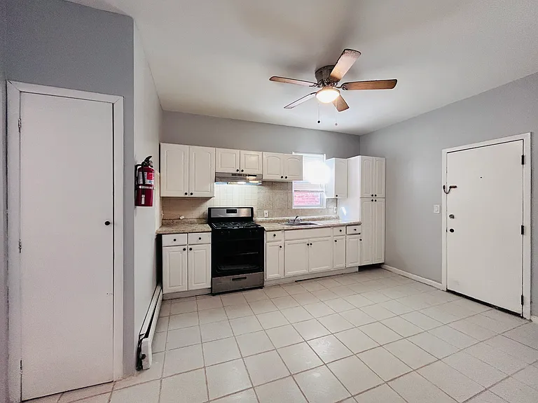 Spacious kitchen with ceiling fan, pantry closet, plenty of cabinets, door on right for basement and backyard access