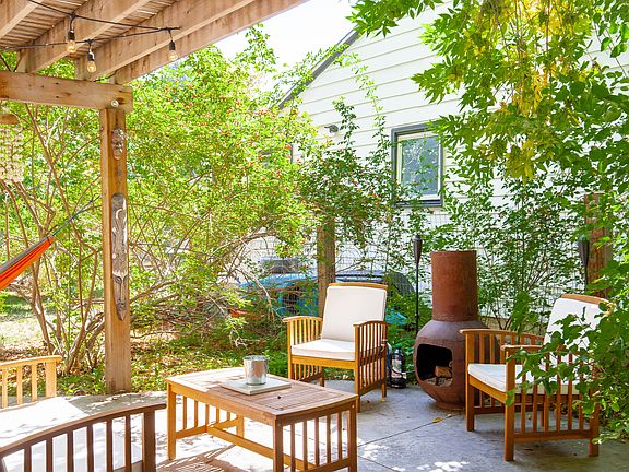 Back patio with pergola, hammock, fireplace, grill, and dining table