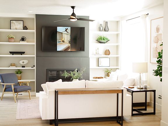 A modern living room from the Contempo Collection features a white sofa, black side table, navy acce