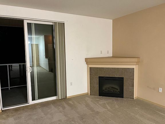 Fireplace in corner of living room. Sliding glass doors to balcony.