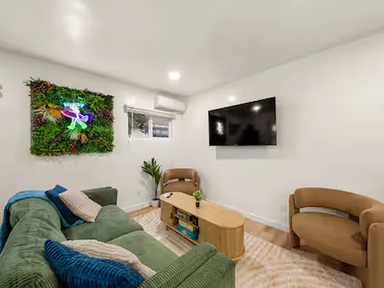 Inviting living room with comfortable seating, a 55" TV, plenty of natural light, and a mini-split AC for year-round comfort, featuring a game table and board games. Perfect space for family and friends to relax, socialize, and play together.