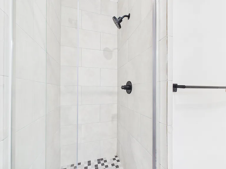 Walk-in shower with tiled surround, mosaic floor, and a glass enclosure for easy cleaning and everyday use.