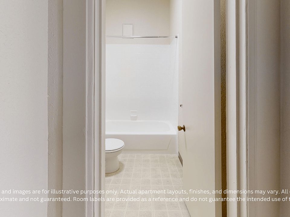 View through an open door into a small bathroom with a bathtub, tile floor, and toilet. The setting is minimal and clean.
