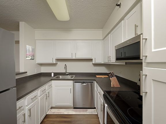 Finish Package III kitchen with white cabinetry, stainless steel appliances, and hard surface plank flooring
