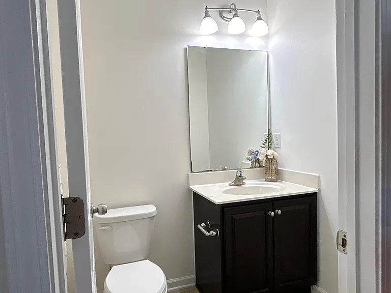 Compact bathroom with a single-sink vanity, large mirror, and overhead lighting for easy daily routines.