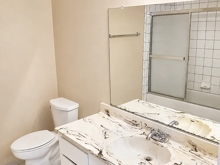 Clean guest bathroom with vanity, mirror, toilet, and tub/shower access.