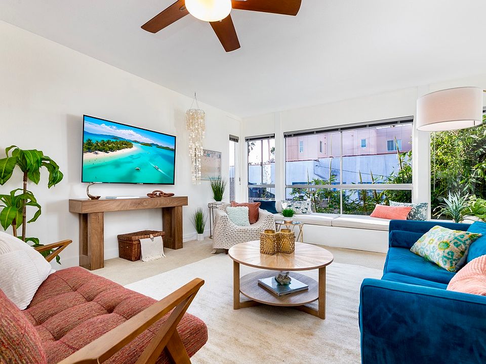 Bright open living area with ocean view, 65" 4K Smart TV, and designer furnishings