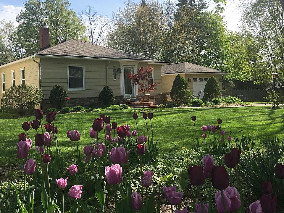 The grassy and very private oversized yard is filled with stately trees and flowering plants.