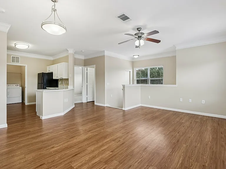 Spacious open-plan apartment living area with elegant wood-style flooring, modern kitchen, and abundant natural light. Spacious open-plan apartment living area with elegant wood-style flooring, modern kitchen, and abundant natural light.