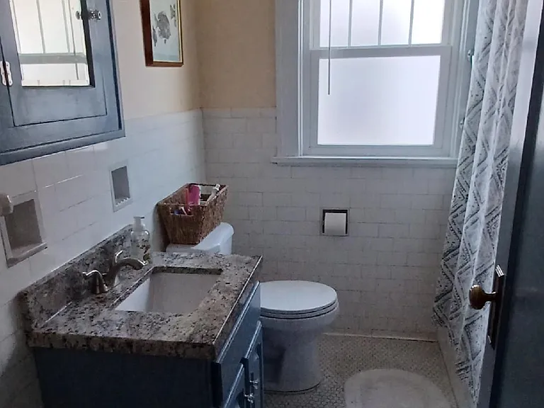 The bathroom has a tub/shower with subway tile surround and excellent exhaust fan, the original built-in medicine cabinet and tile floor. The sink has a marble top.