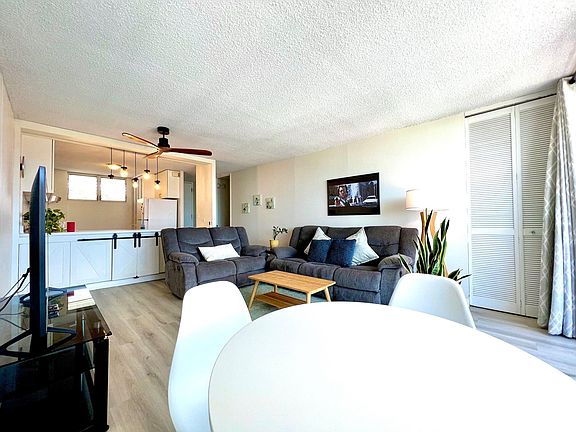 Living Room. 2 Reclining sofas, coffee table, 58" Smart TV w/ stand, ceiling fan, dining table w/ 4 chairs (view from dining area)