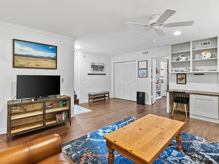 Second living room with two desk spaces, comfortable leather couch and lounge chair, Smart TV, and a ceiling fan. Perfect spot for movie night.