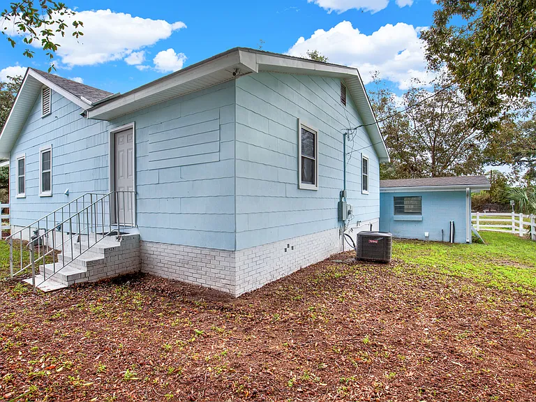 Back and side of home with lighting and 4th entry door. Separate utility room with new washer and dryer. Plenty of storage.