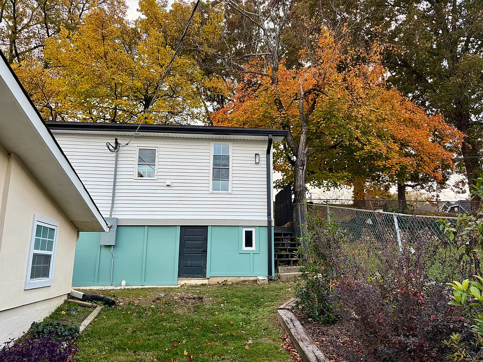 Duplex & yard in front, Tremont-facing side of house with crawlspace door & window shown