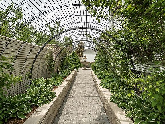 Walk through the covered iron arbor to the private courtyard! Flowered plantings will shade walkway in the coming months!
