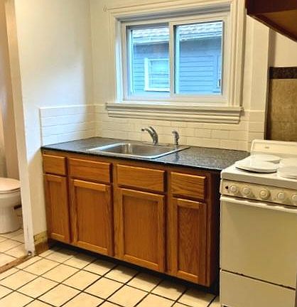 Kitchen area with natural light and bathroom enterance, both areas have ceramic tile flooring