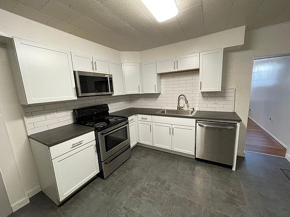 fully equipped kitchen with stainless appliances and shaker cabinets