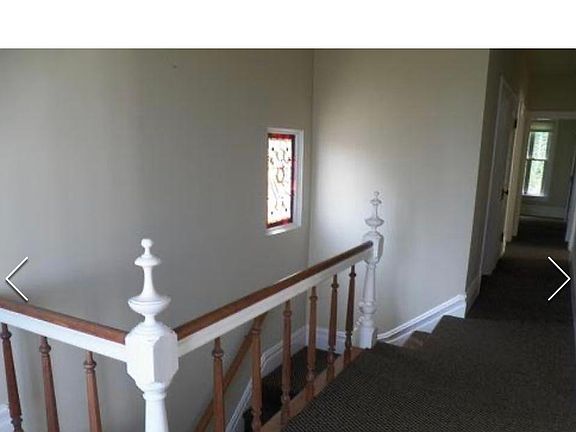 Hallway to bedrooms, kitchen and bathroom. Stairs go downstairs to from door and basement with lots of storage