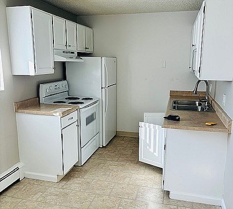 Charming and efficient kitchen with white cabinetry, modern appliances, and ample countertop space.