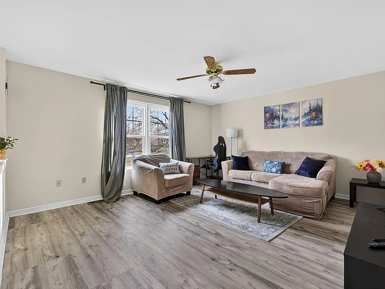 Spacious living room with large window, seating area, and TV setupideal for relaxing or sharing the space comfortably.