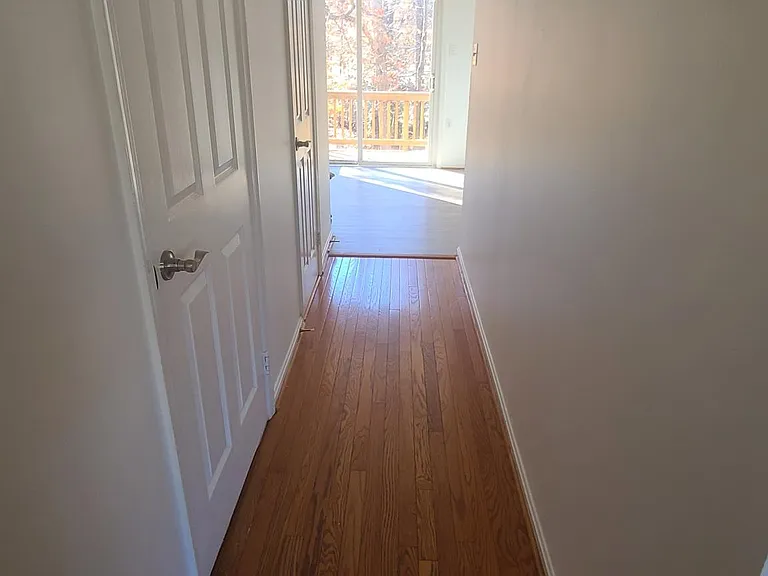 Hallway view from front door. First left door leads to basement. Followed by powder room bath, then kitchen leading out to upper deck facing wooded lot.