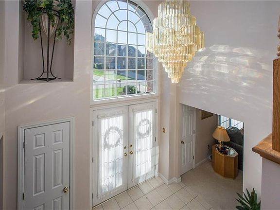 The tiled two-story foyer offers an inviting, airy entrance. Guest coat closets flank the front doors. A lovely drop chandelier 