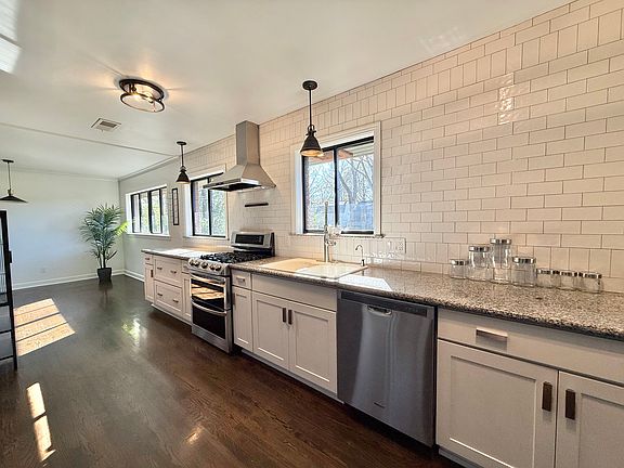 Chef's Kitchen featuring Full wall of Hand tumbled Zelig like Subway Tile- Custom Cabinets, SS Dishwasher, SS Double Ovens/Gas Range, White Cast Iron Sink, Pendant Lighting over Granite counters.