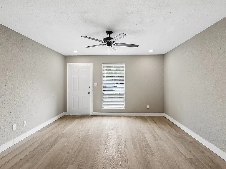 Bright modern room with elegant wood flooring, neutral walls, and a sleek ceiling fan, inviting and move-in ready.