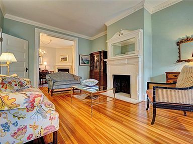 Front parlor with decorative fireplace has gorgeous honey colored floors and is freshly painted