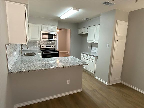 Kitchen featuring visible vents, a peninsula, a sink, electric stove, and stainless steel microwave