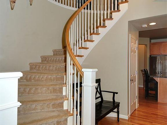 Dramatic open spindle stairway curves gently toward the foyer