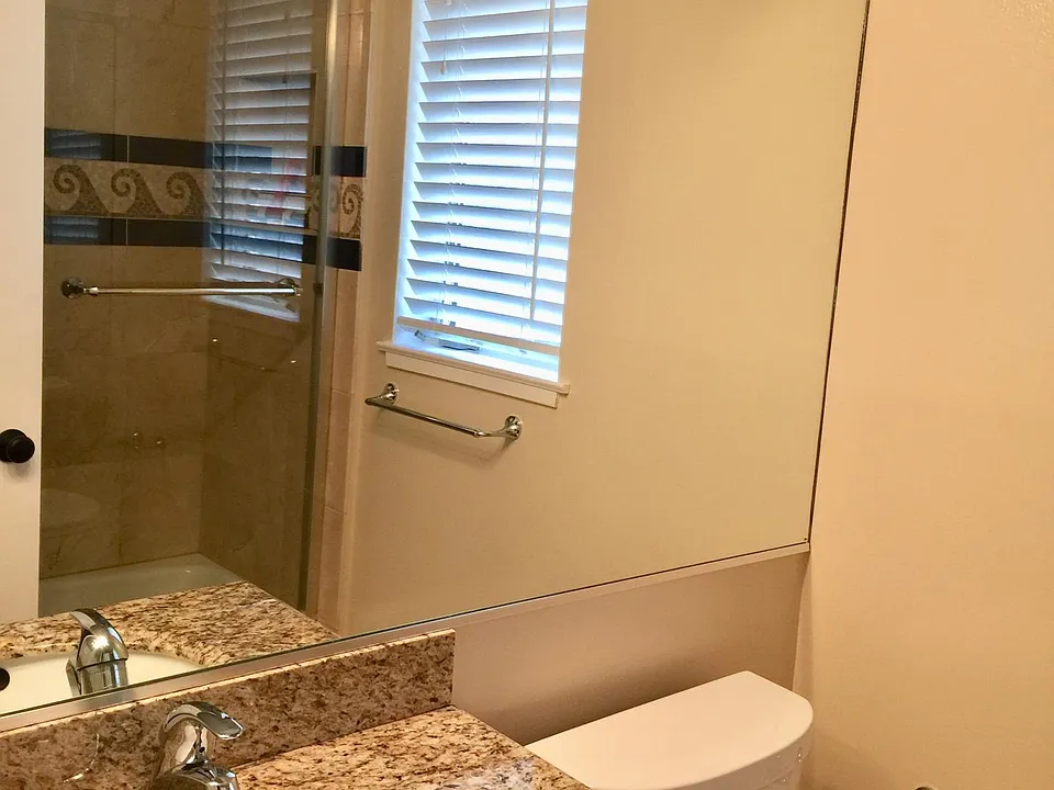 Granite and marble bathroom with tub/shower in inlaid wave design, clear glass shower doors