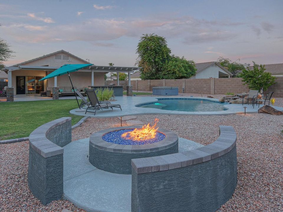 Firepit and pool with grassy yard.