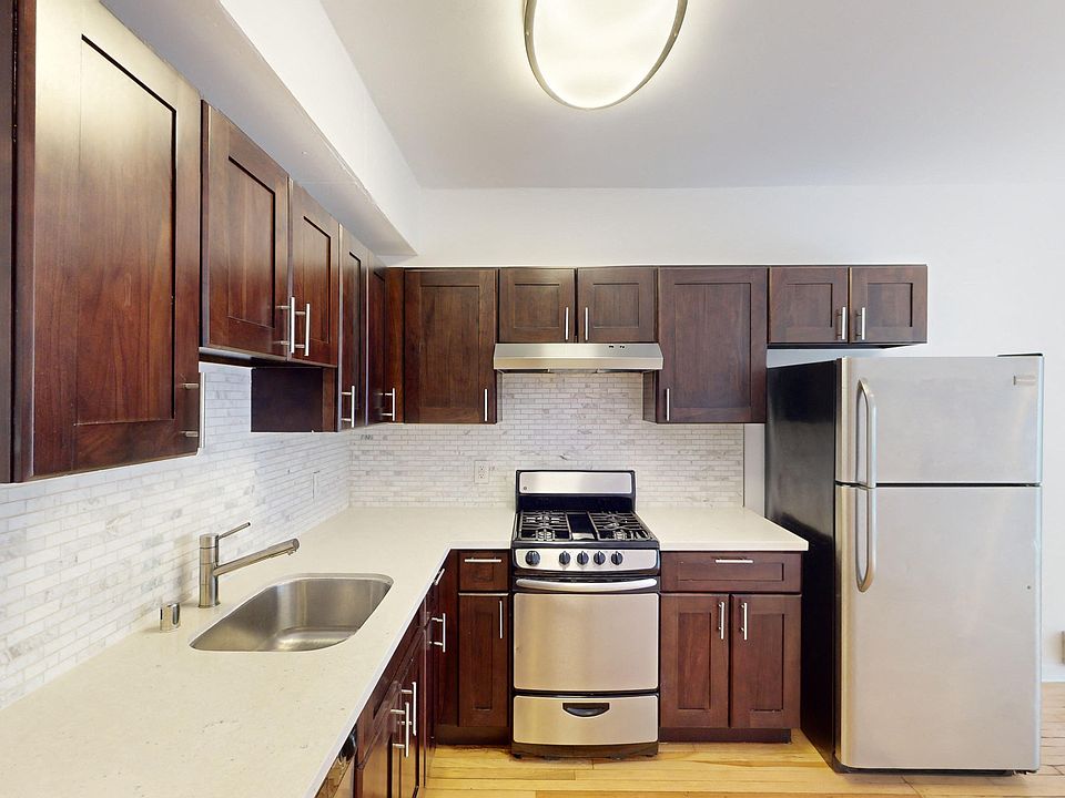 Kitchen with cabinets, refrigerator, stove, range hood, and sink