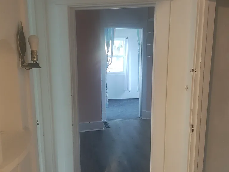 view towards kitchen and small back porch dining area. Basement door on right. Bedroom door on left. Old school telephone nook on left.
