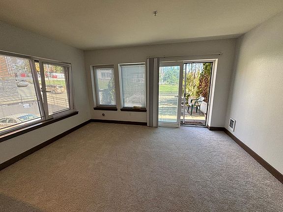 Living room leading to a large patio area with view of the Seattle Great Wheel and cruise ships
