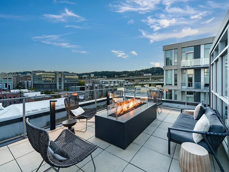 A rooftop fire pit at Modera Pearl with city views and comfortable seating, offering an inviting spot to gather as the evening sets in.