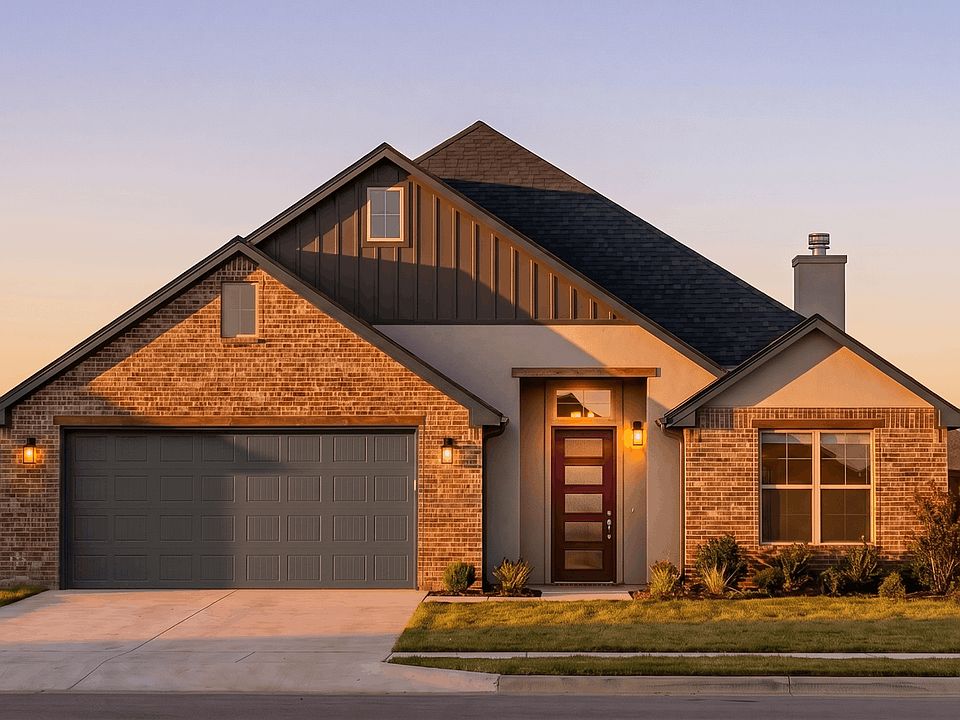 Modern brick house with a dark gray roof, large garage, and illuminated front door at sunset. The ho