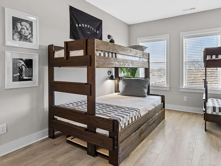 Shared bedroom with sturdy bunk beds, wood-look flooring, and large windows with blinds for natural light and privacy.