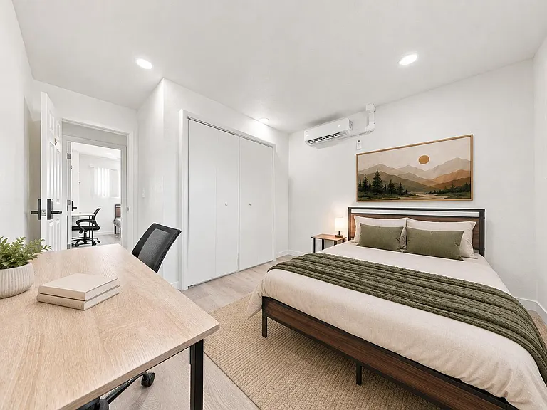 Furnished bedroom with a dedicated desk, large closet, and efficient mini-split A/C, plus a window for natural light.