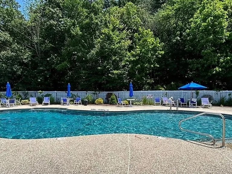 In-ground pool with seating, umbrellas & lifeguard on duty