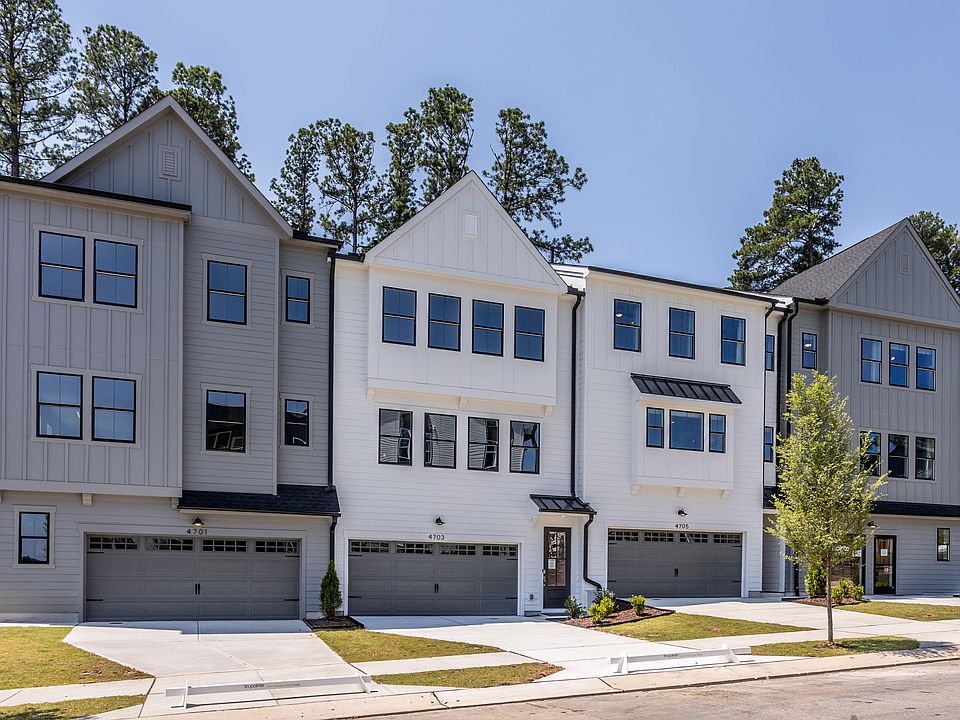 The image depicts a row of modern, multi-story townhouses with gray siding, large windows, and attac