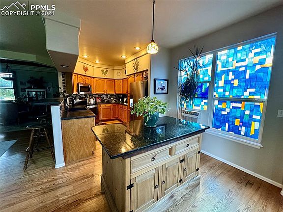 Galley kitchen with oak cabinets, electric stainless steel appliances, custom granite island