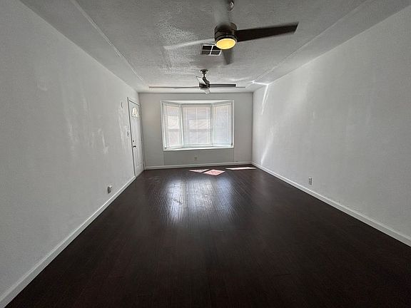 Living room with hardwood floor and 2 ceiling fans with remotes.