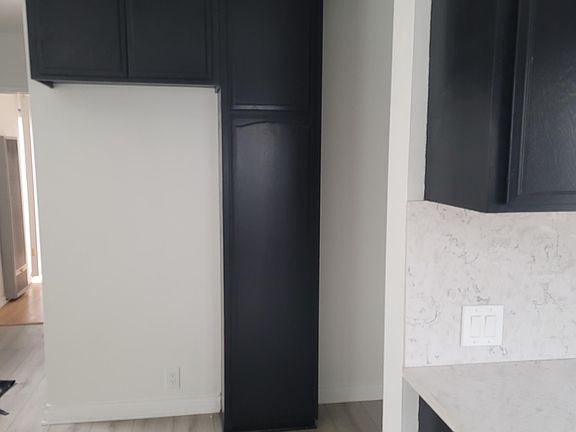 Ample space for a refrigerator underneath cabinets and next to utility closet.