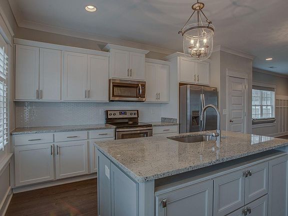 Kitchen view from front door. Both Windows in kitchen are custom shuttered louvered window treatment.