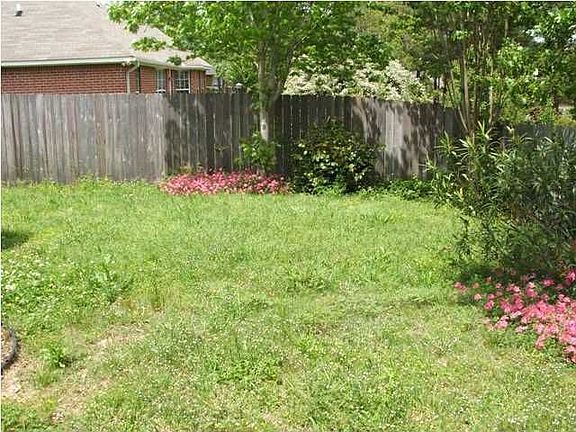 Privacy fenced backyard with lush landscaping.