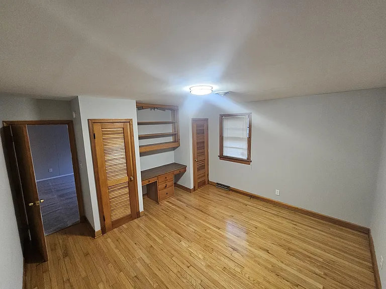 Bedroom with built in office/desk area and shelving.