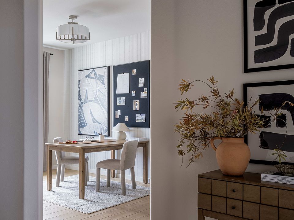 A cozy and well-designed living space with a wooden table, chairs, and a decorative vase in the fore
